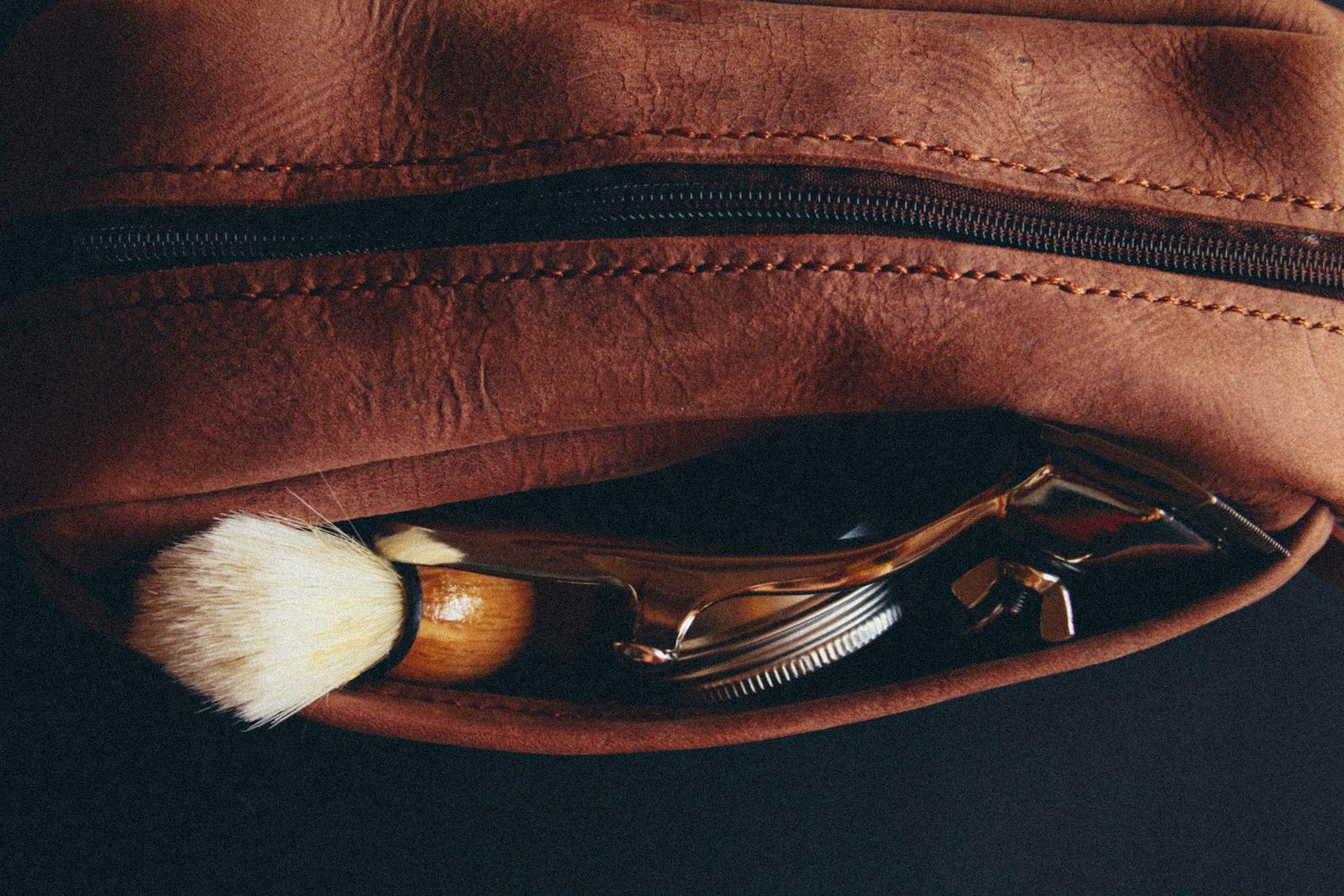A shaving brush and razor tucked into a rolled leather case