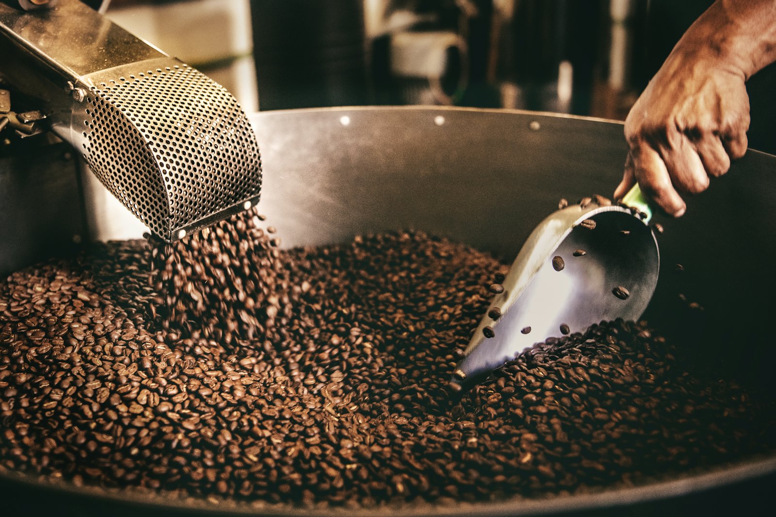 Roasted beans tumbling into the cooling tray, a scoop turning them through